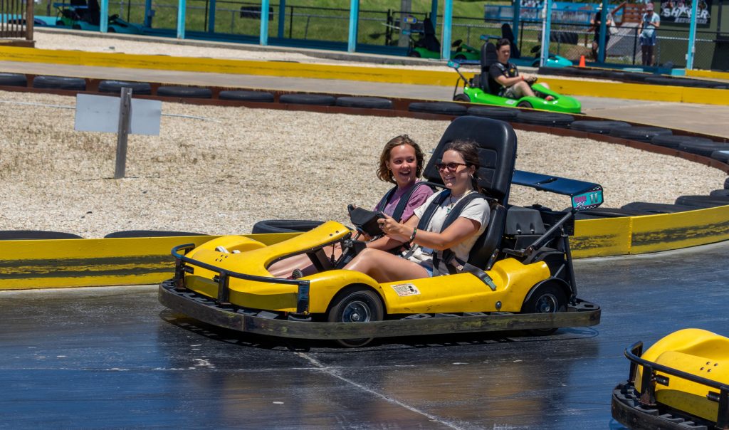 Two girls in a yellow go cart smiling
