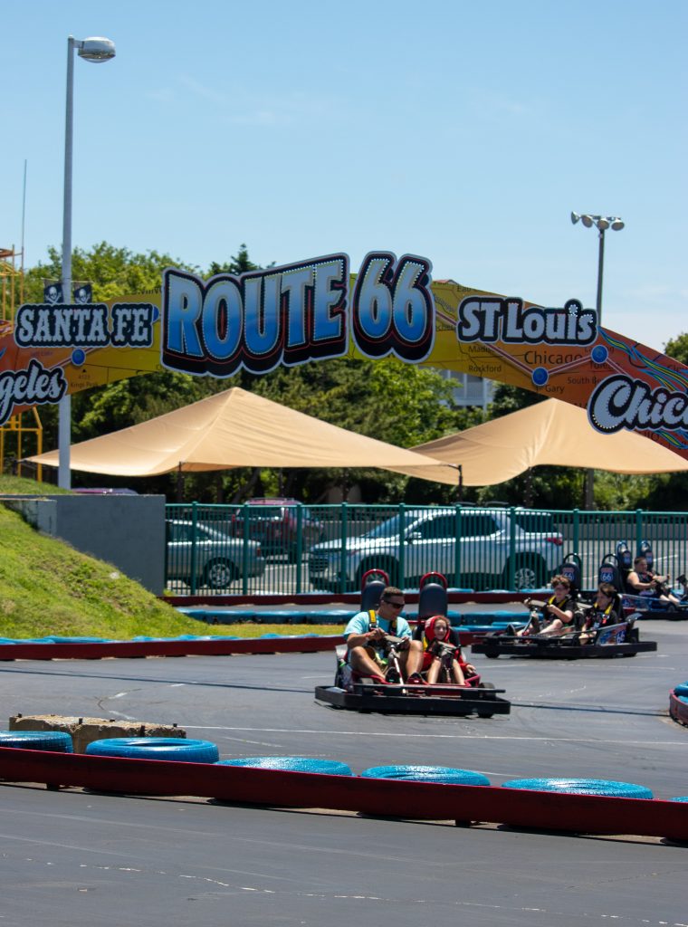 People racing on track with Route 66 Sign above them